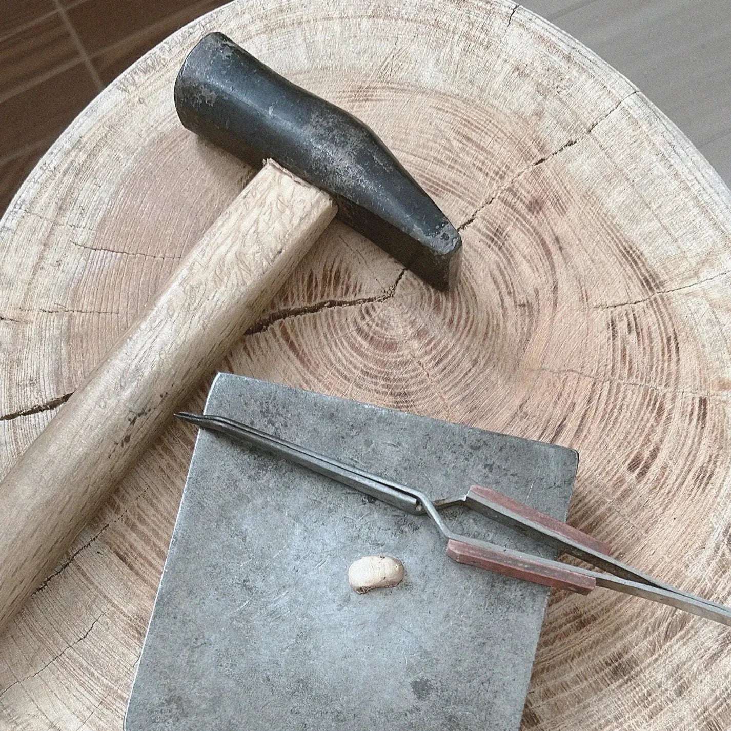 Hammer, chisel, and tongs on a wooden anvil
