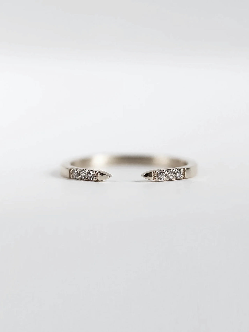 Silver ring with small diamonds on a light gray background
