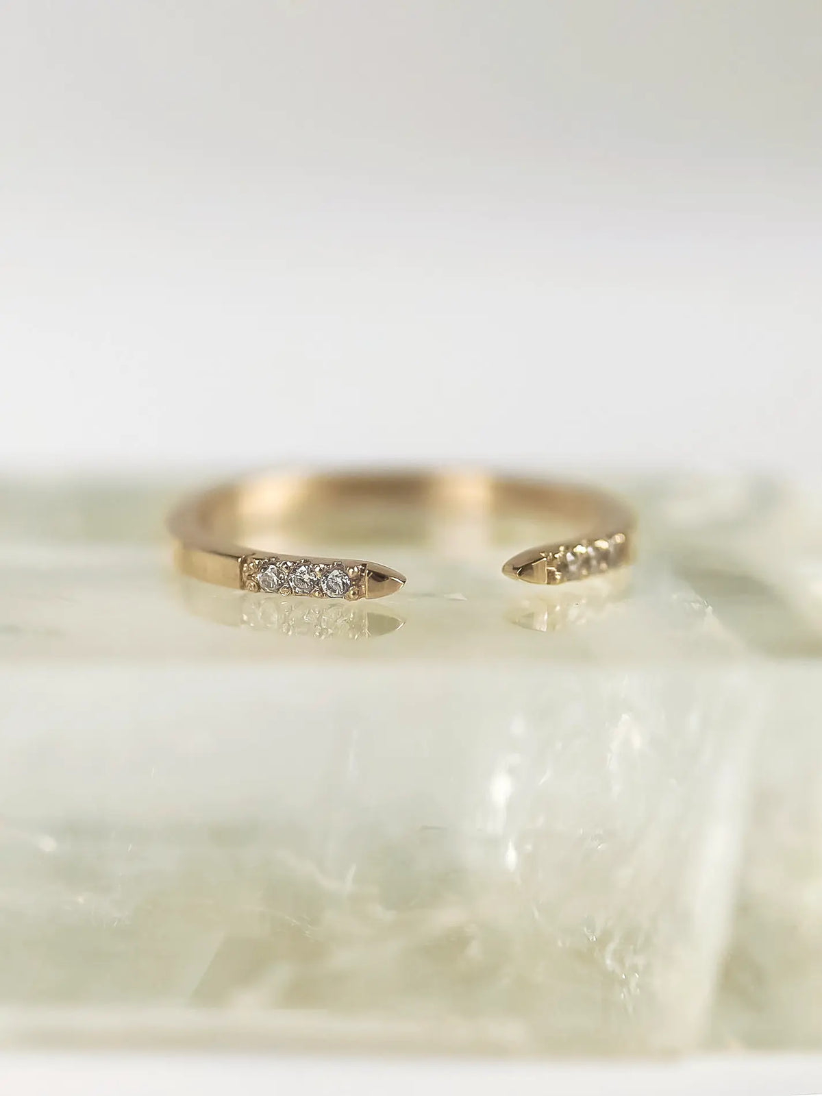 Gold ring with small diamonds on a light marble surface