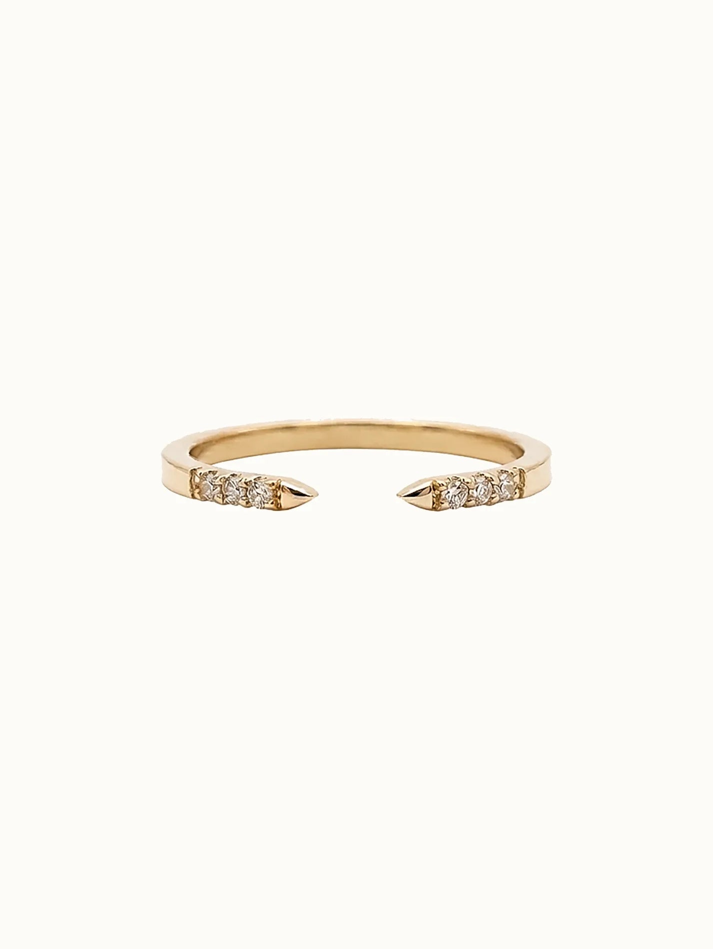 Gold open-ended ring with diamond accents on a white background