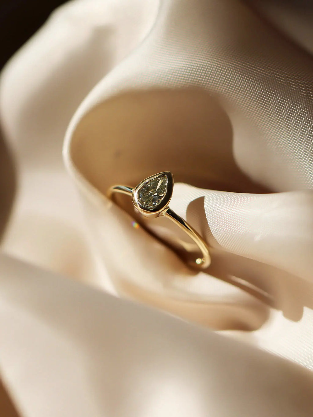 Gold ring with a heart-shaped diamond on a soft fabric background