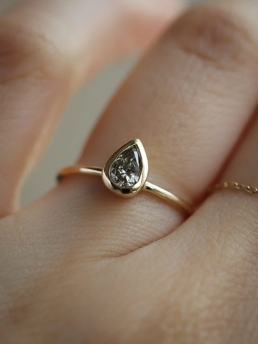 pear bezel set diamond ring on a finger