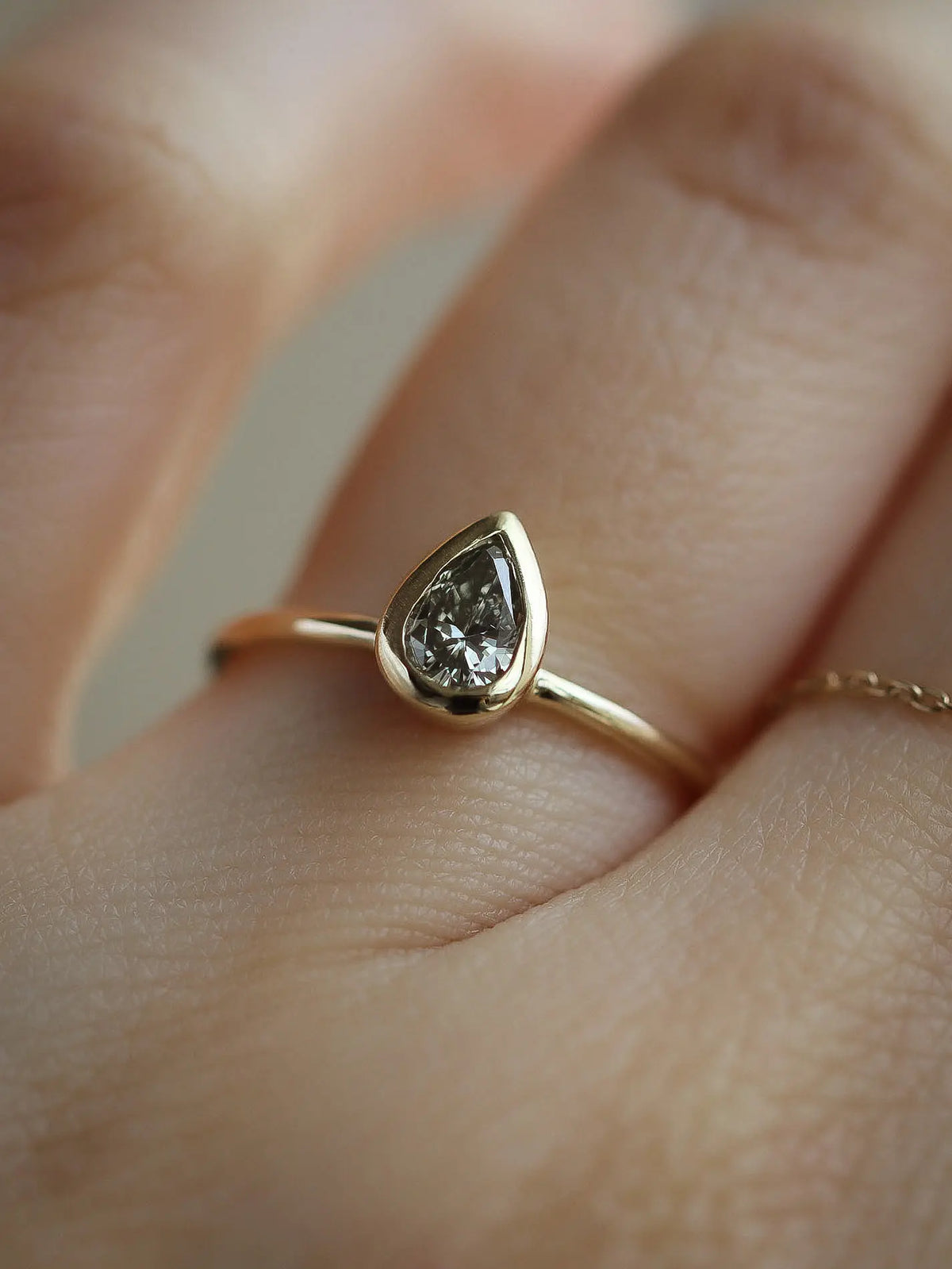 pear bezel set diamond ring on a finger