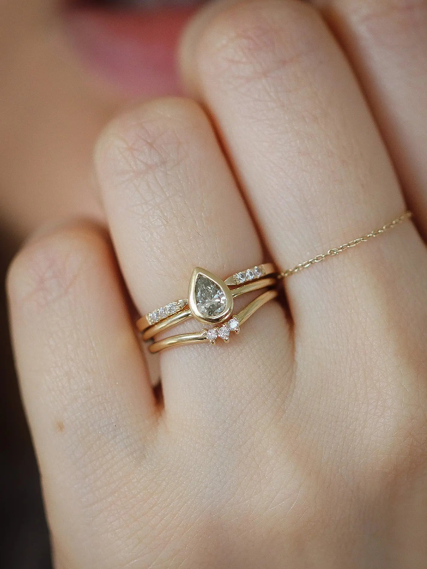 Gold ring with a teardrop-shaped diamond on a finger