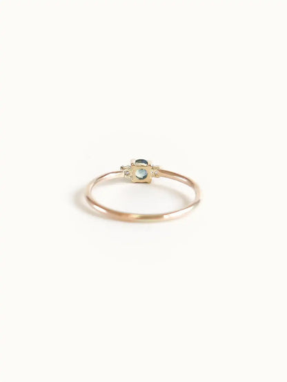 A classic teal blue green three-stone Sapphire ring with diamond accents.