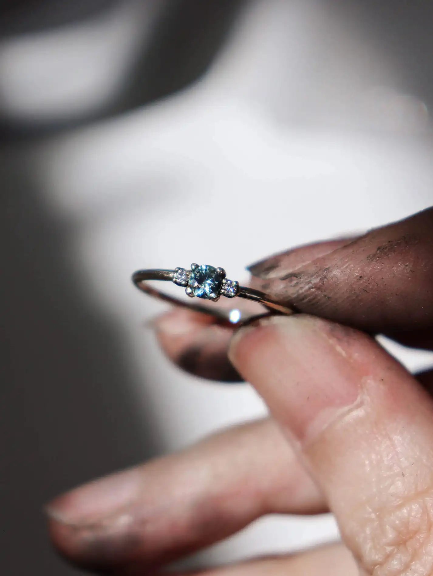 A classic teal blue green three-stone Sapphire ring with diamond accents.