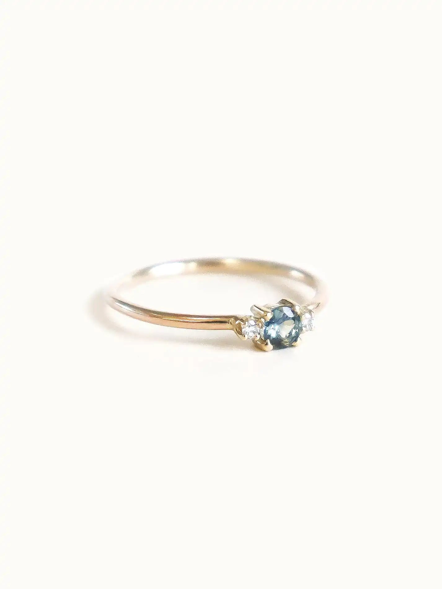 A classic teal blue green three-stone Sapphire ring with diamond accents.