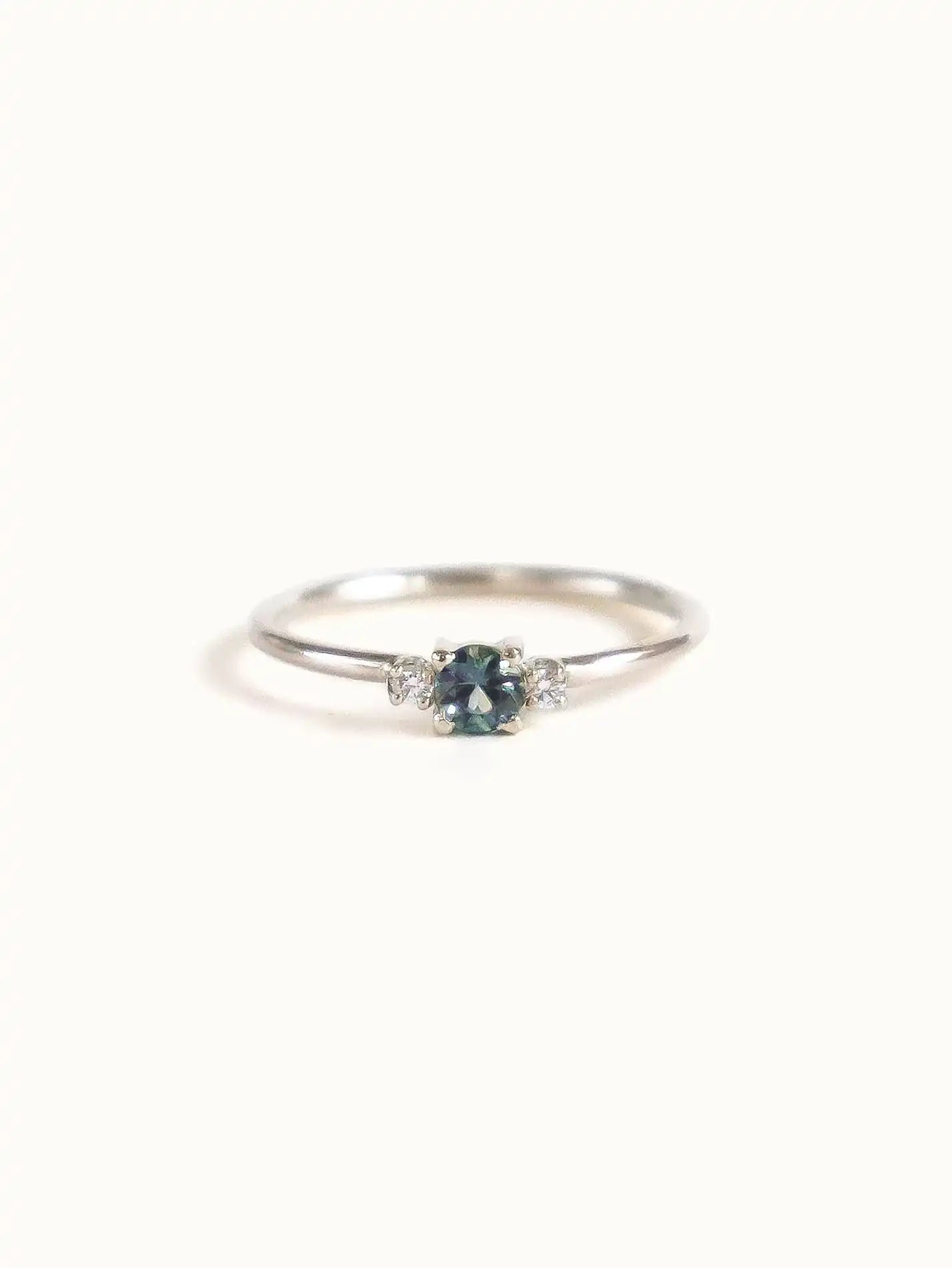 A classic teal blue green three-stone Sapphire ring with diamond accents.